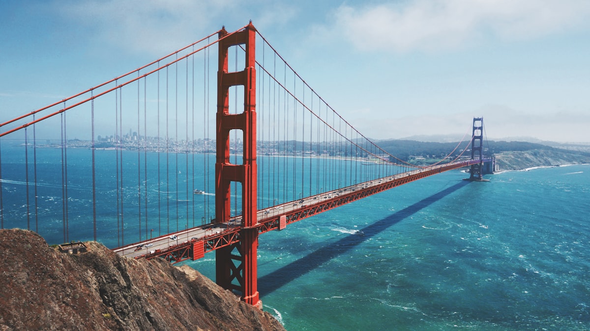 Golden Gate Bridge at golden hour with fog rolling beneath the towers